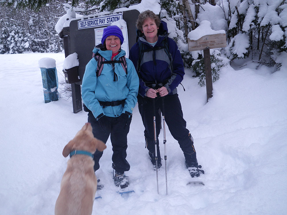 two hikers and a lab at the trailhead in winter conditions