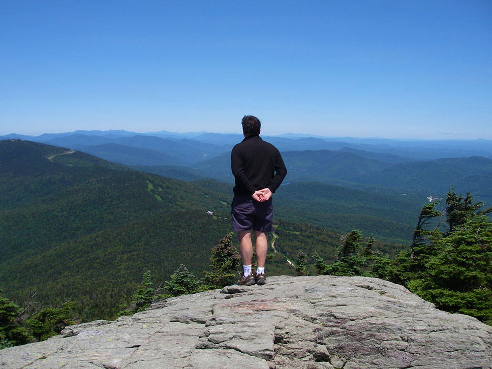 Views hiker standing on ledge looking out towards valley views