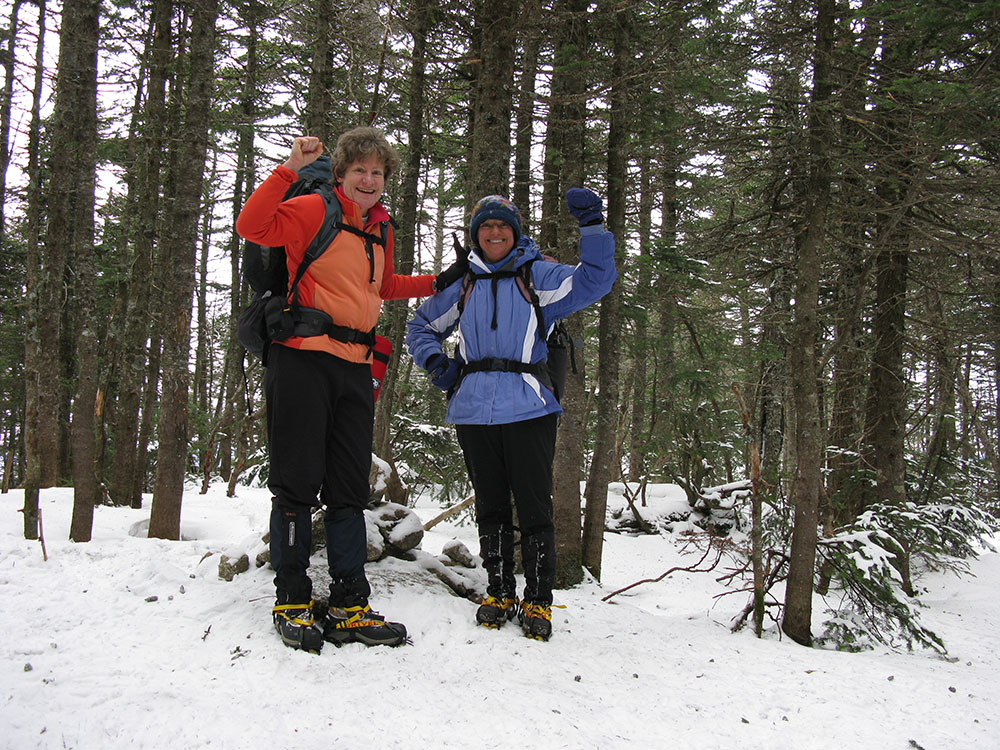 two hikers at the summit of East Osceola in winter