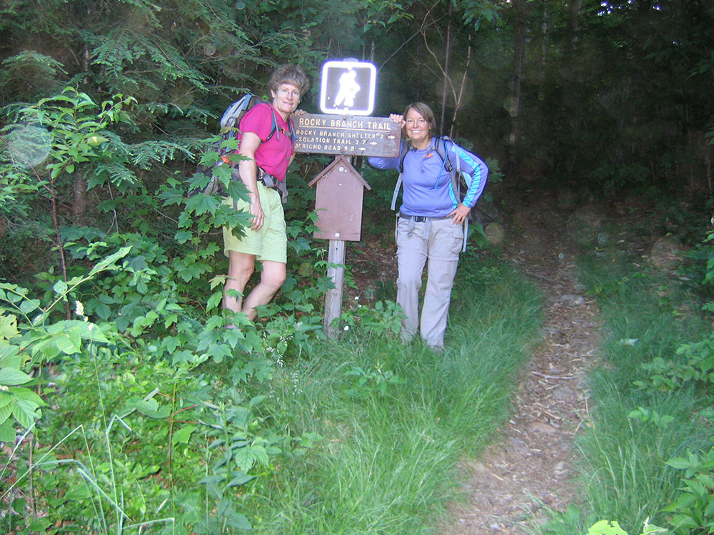 two hikers at the trailhead sign