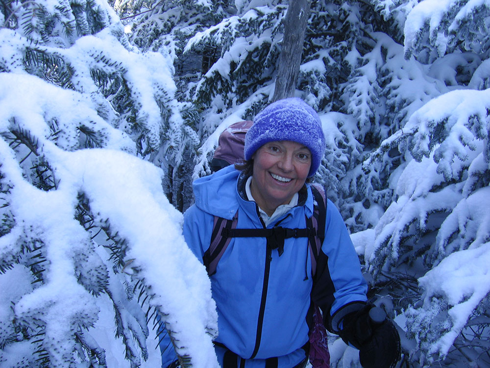 hiker posing amidst evergreens coated in snow