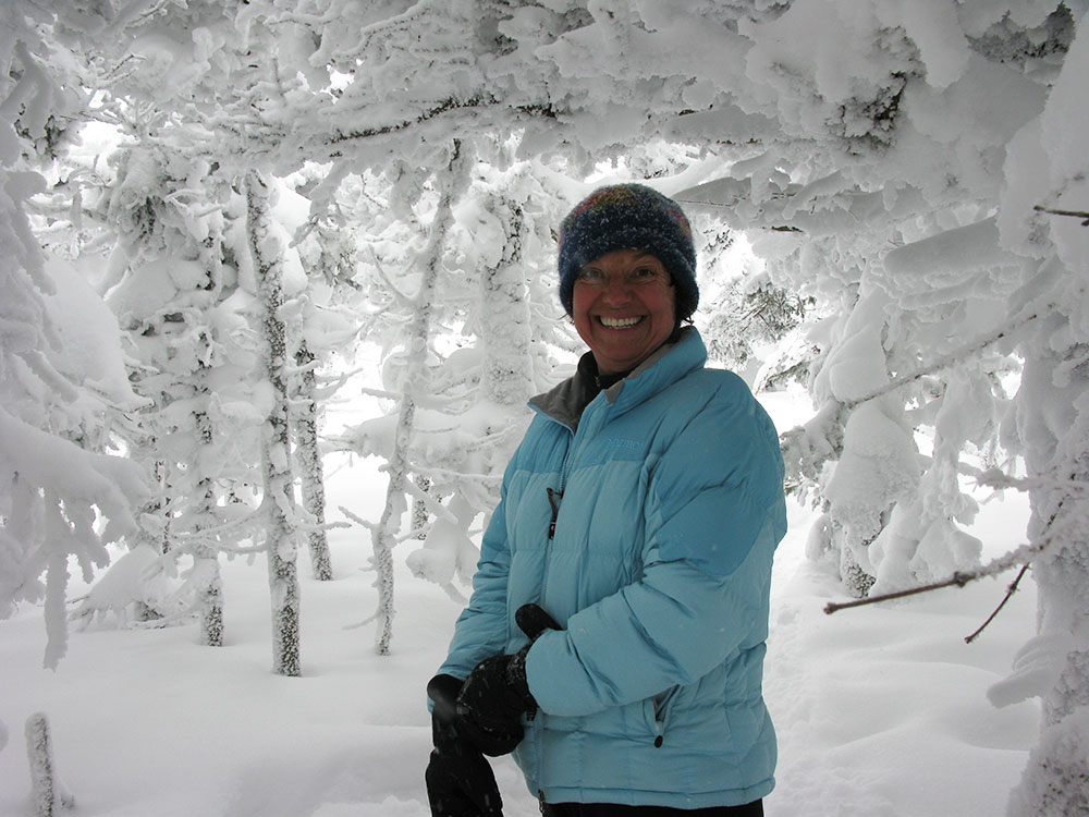 Nancy hiker putting on gloves under a bower of snow covered branches