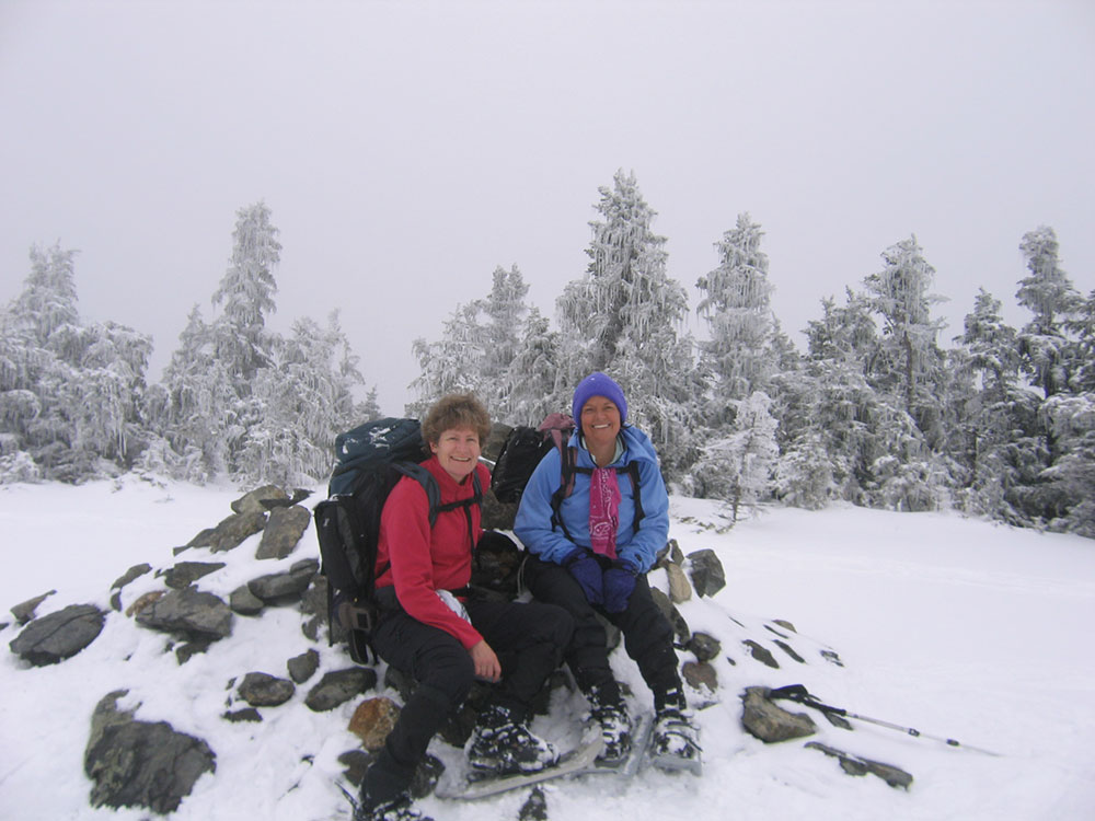 two hikers sitting on the cairn at the summit of Mt. Hale in the White Mountains