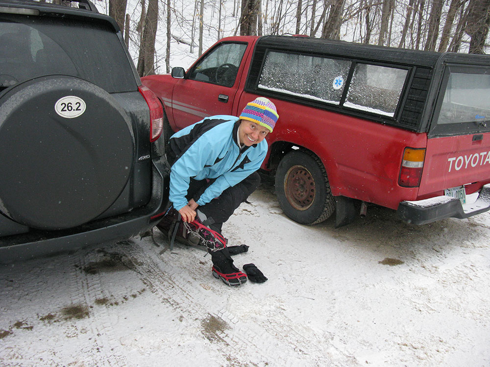 hiker putting on microspikes in the parking lot at teh trailhead