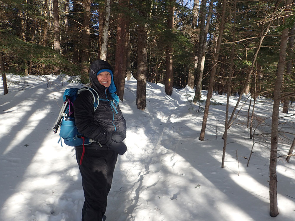 Nancy hiker bundled in warm clothes standing on snowy trail in winter