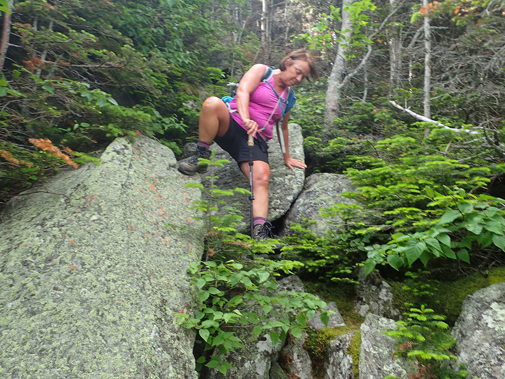 hiker descending the rocky boulder field of Chandler Brook Trail