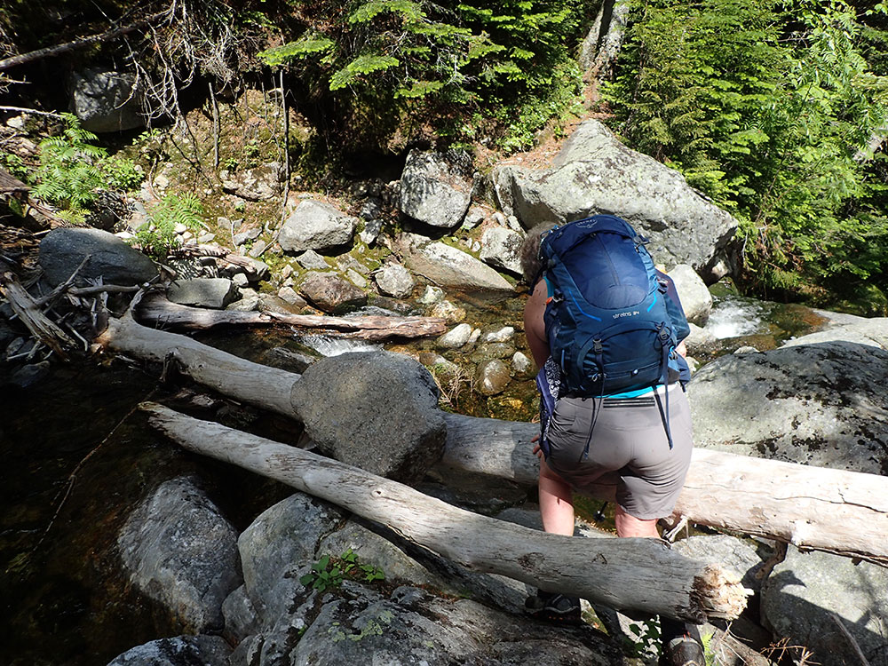 hiker crossing a stream seen from behind