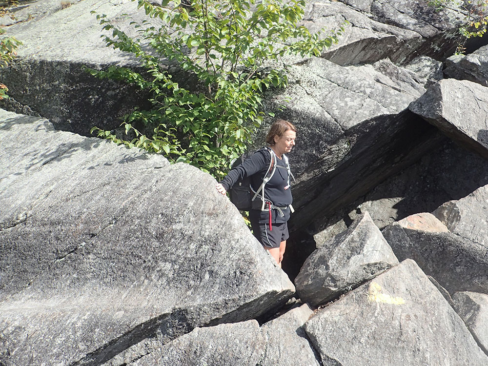 hiker climbing out from caves onto slab rock