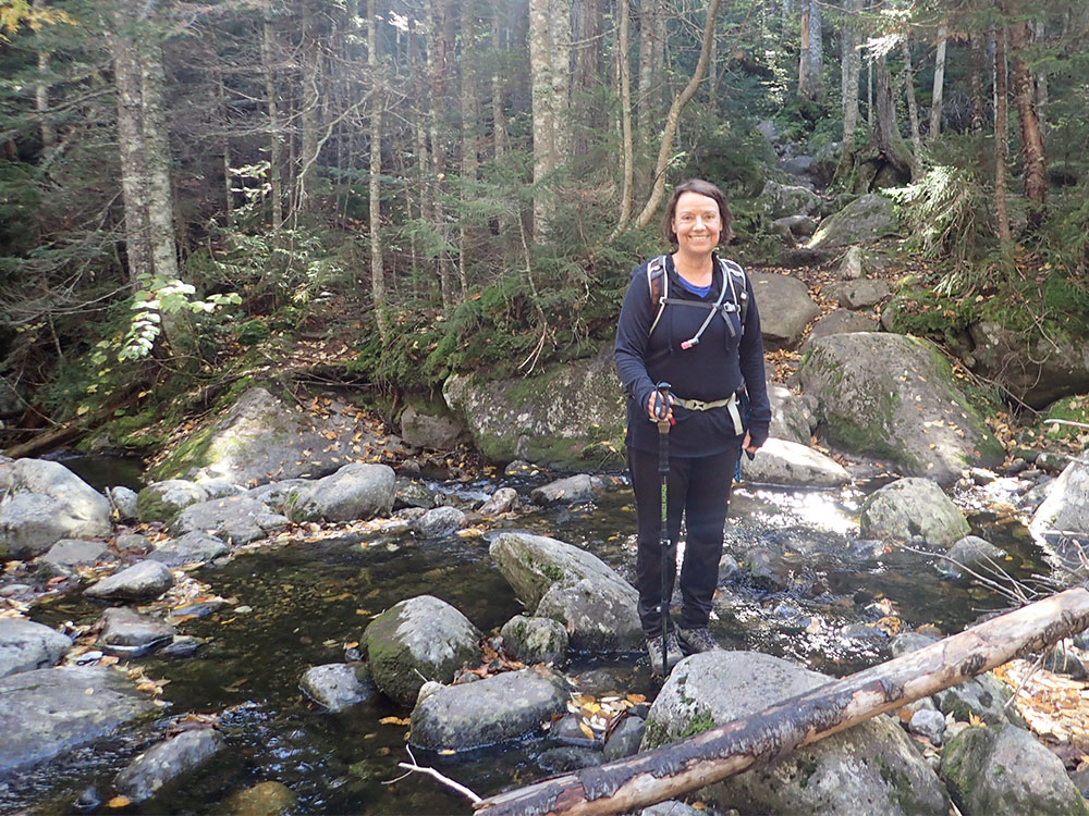 hiker ccrossing a stream on the Great Gulf Trail