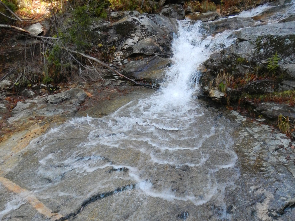 waterfall creates patterns of itself on rocks below