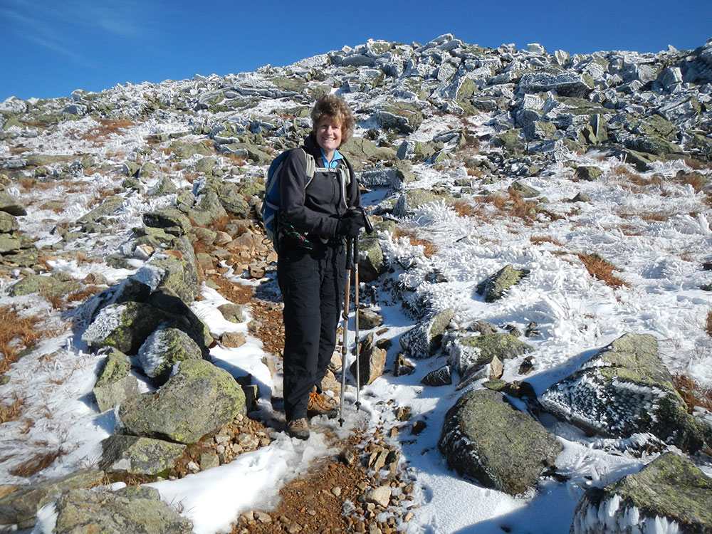 hiker on trail with rocks covered in rime ice