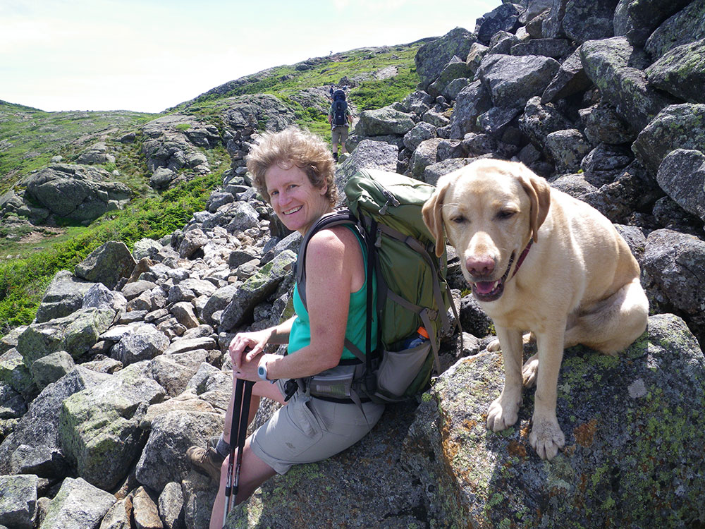 Pat and Dejah hiker and yellow lab resting on a rock above tree line
