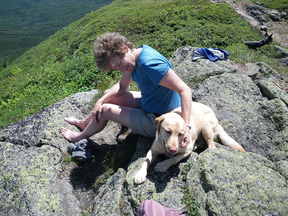 Pat and Dejah hiker in bare feet petting yellow lab and resting