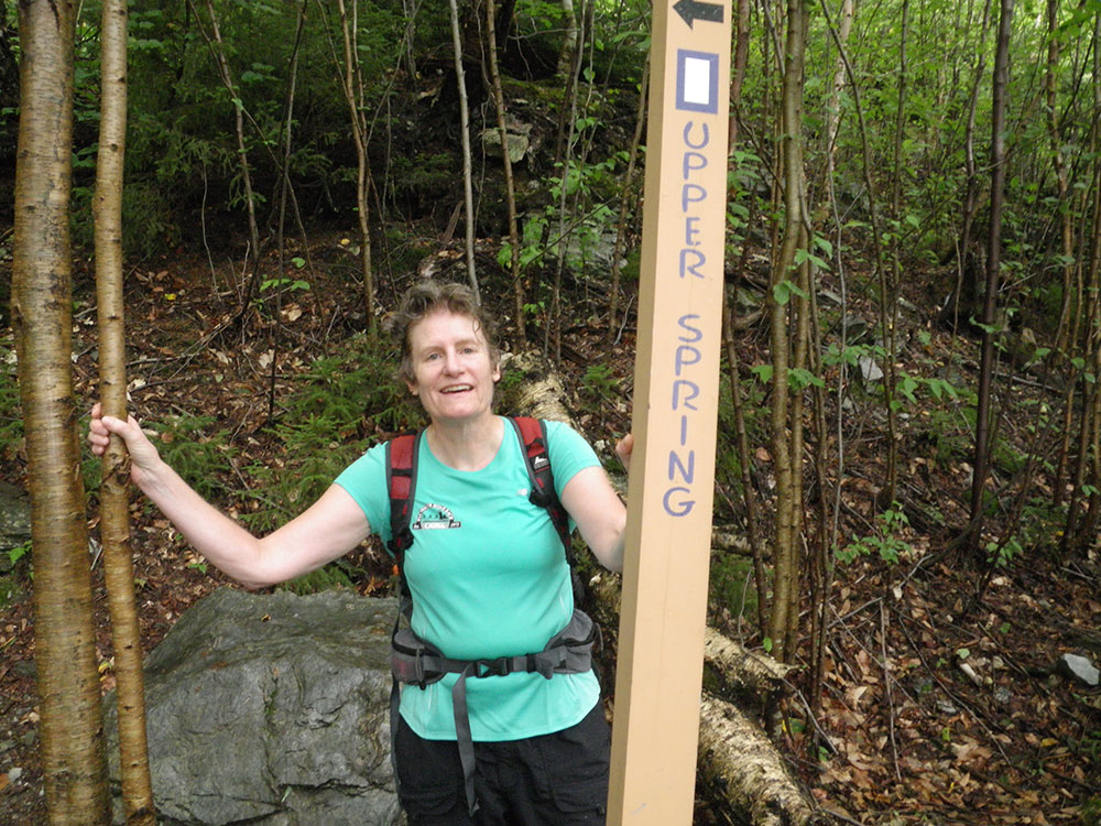 hiker posing next to trail sign