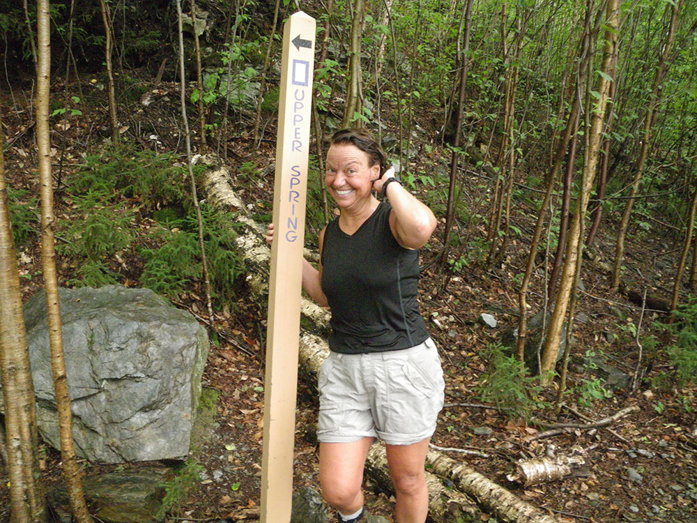 hiker posing near trail sign