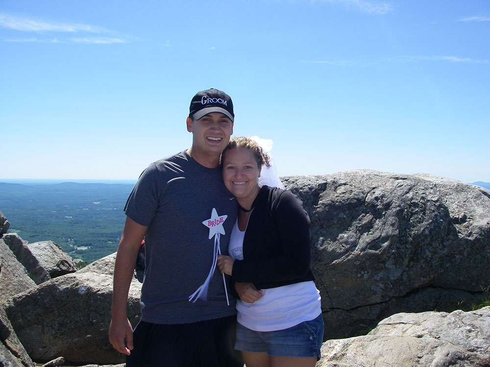 bride and groom posing on top of mountain