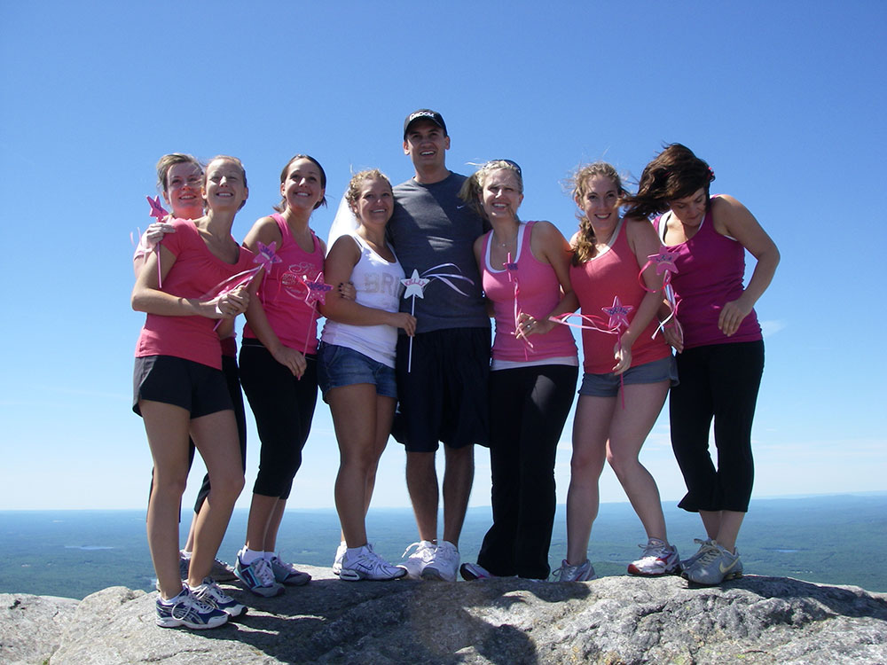 bride, groom, and maids of honor posing atop a mountain