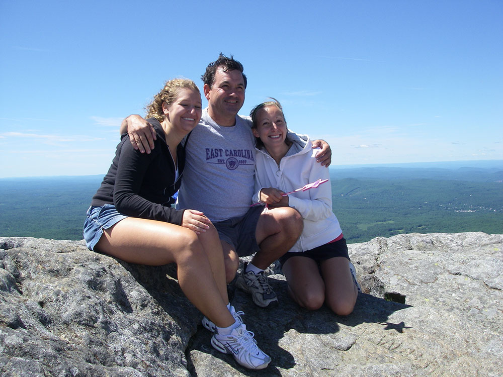 three hikers posing on top of mountain