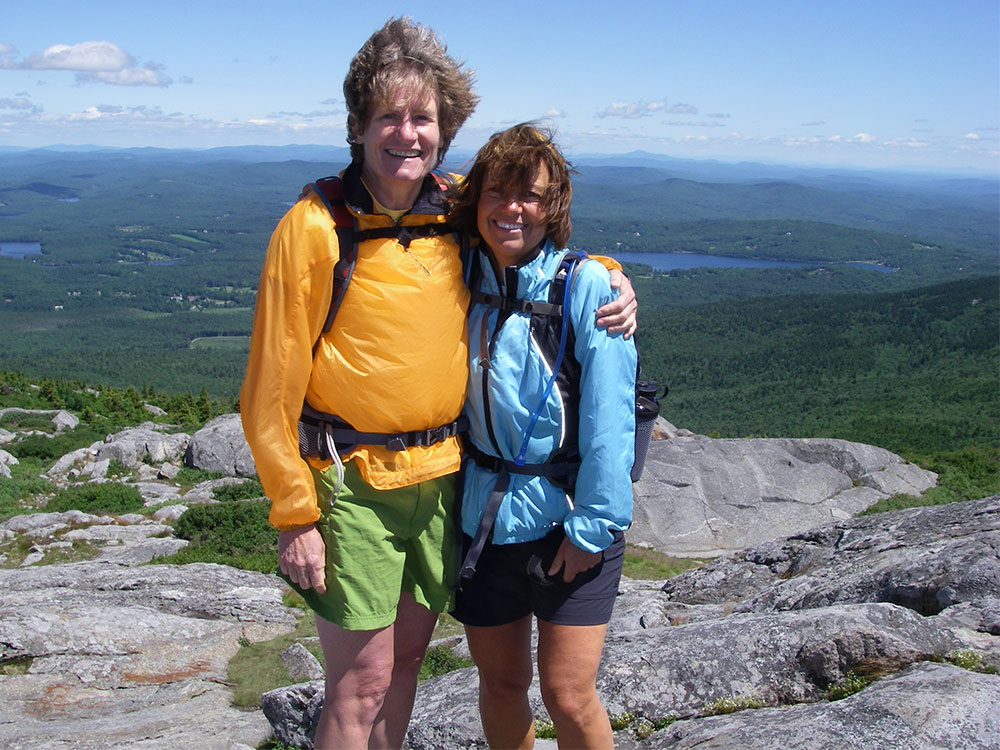 two hikers posing above tree line on a mountain top