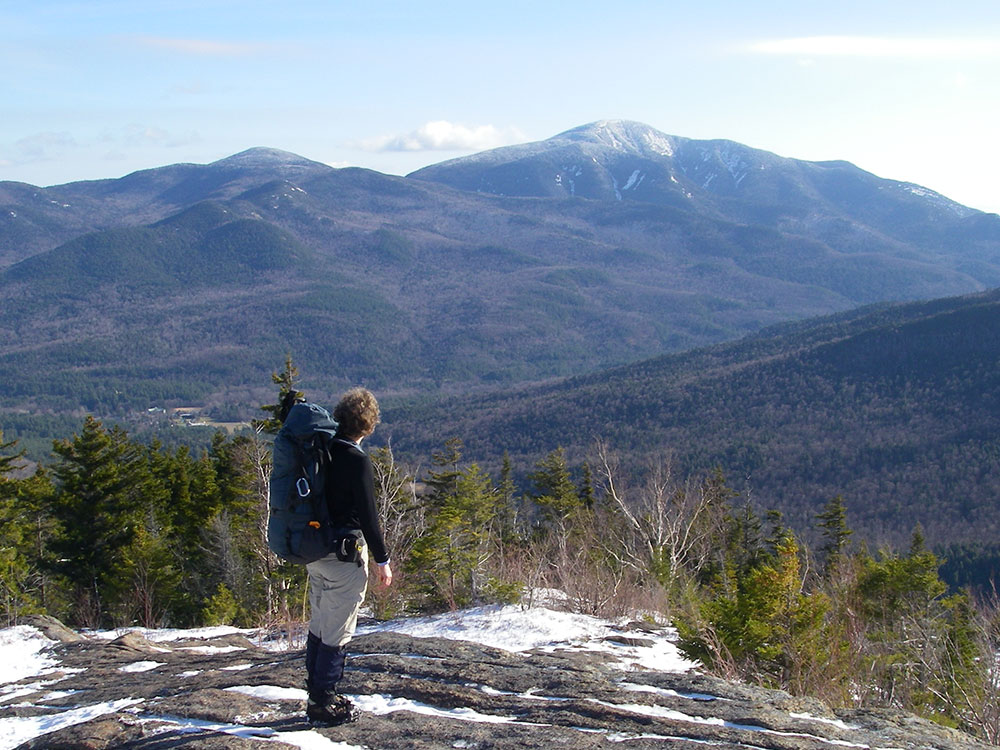 hiker looking outward in the foreground and the Adirondacks on display