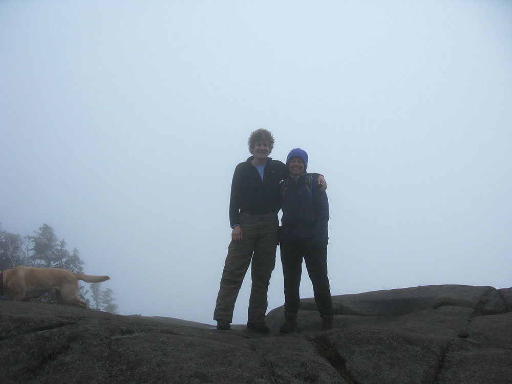 two hikers standing on a rock in shadow