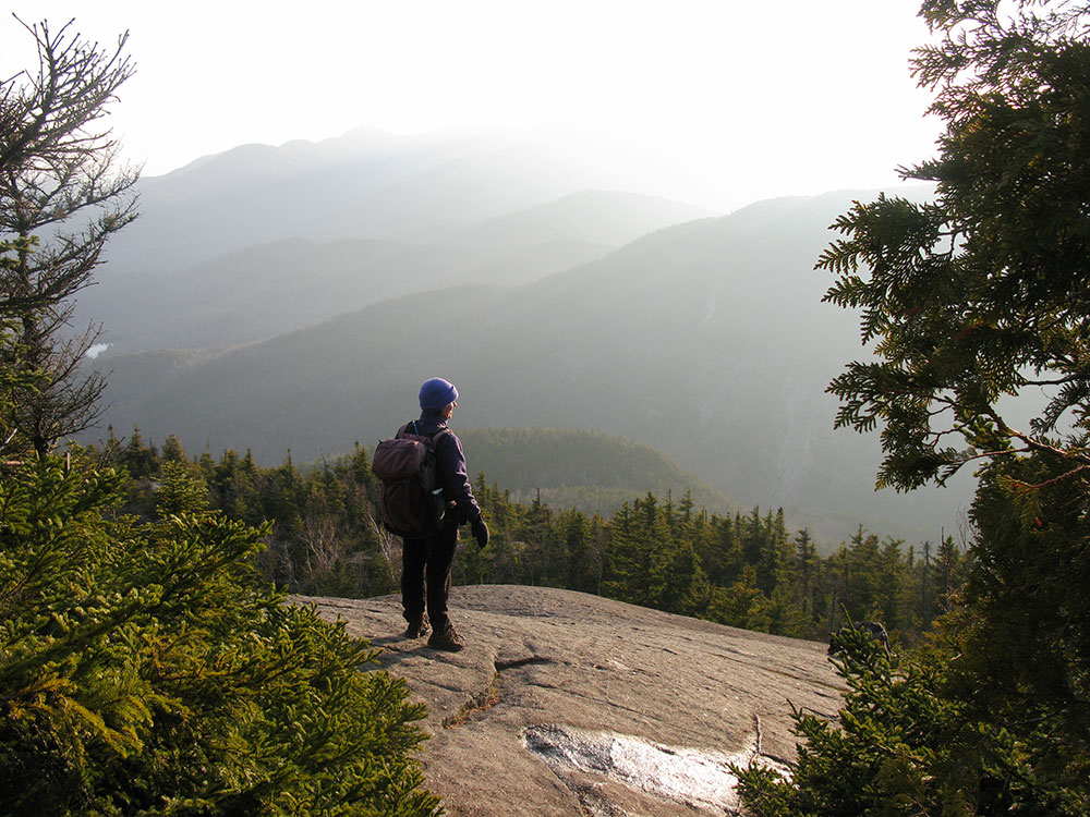hiker standing on a slab looking out toward the mountains