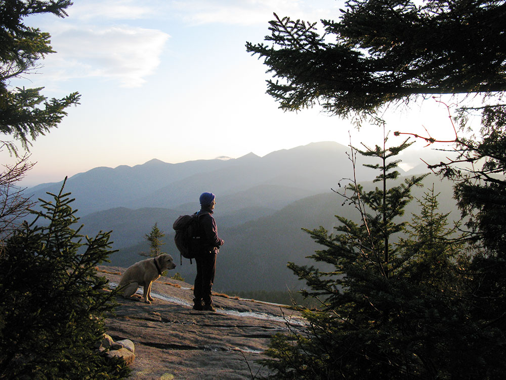 hiker standing on a slab looking out toward the mountains