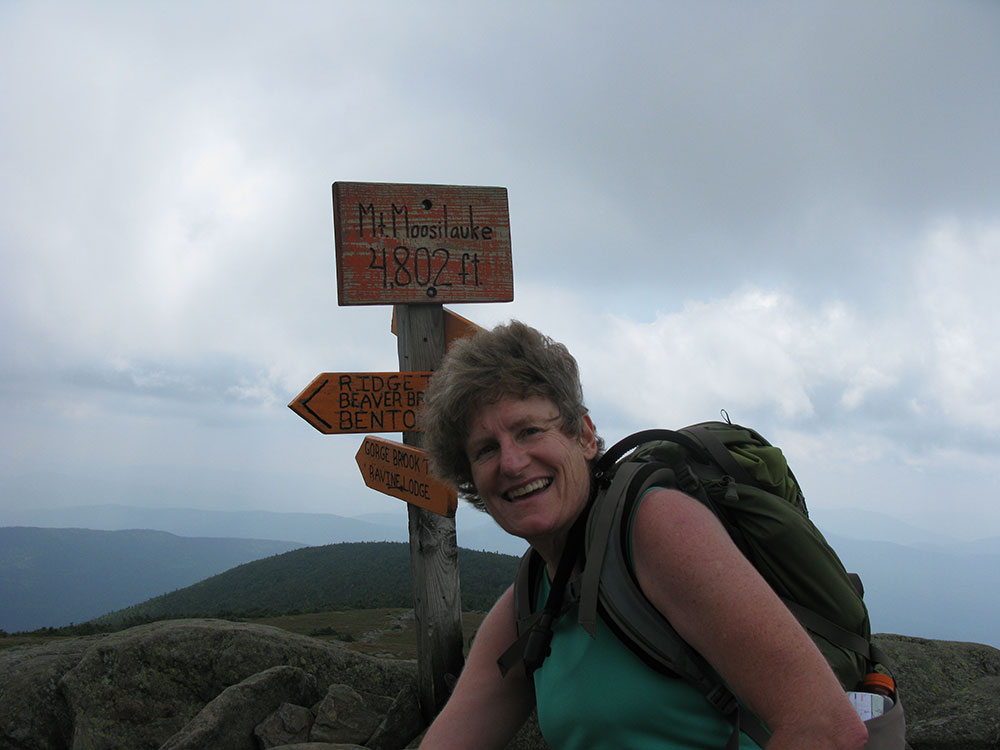 hiker posing next to summit sign on Mt Moosilaukee