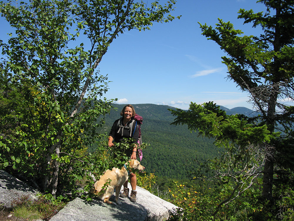 hiker and yellow lab standing on a slab on the ledges