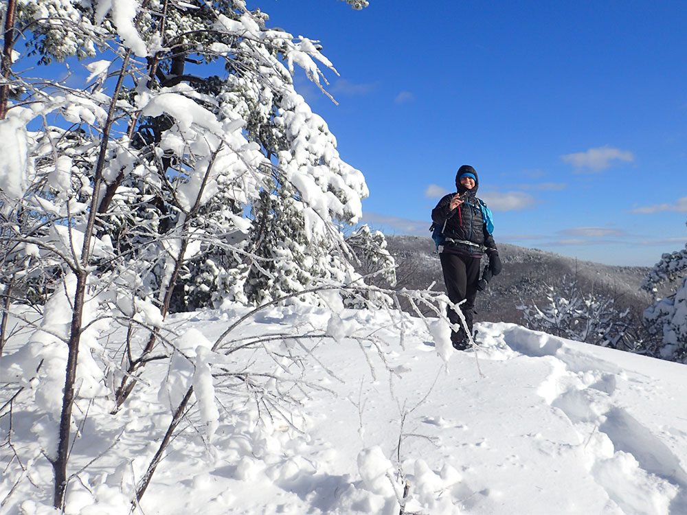 Nancy hiker on snowy trail above treeline in winter