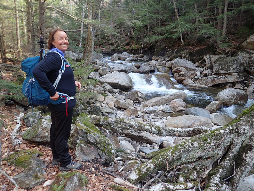 hiker standing on the bank of a fast flowing stream