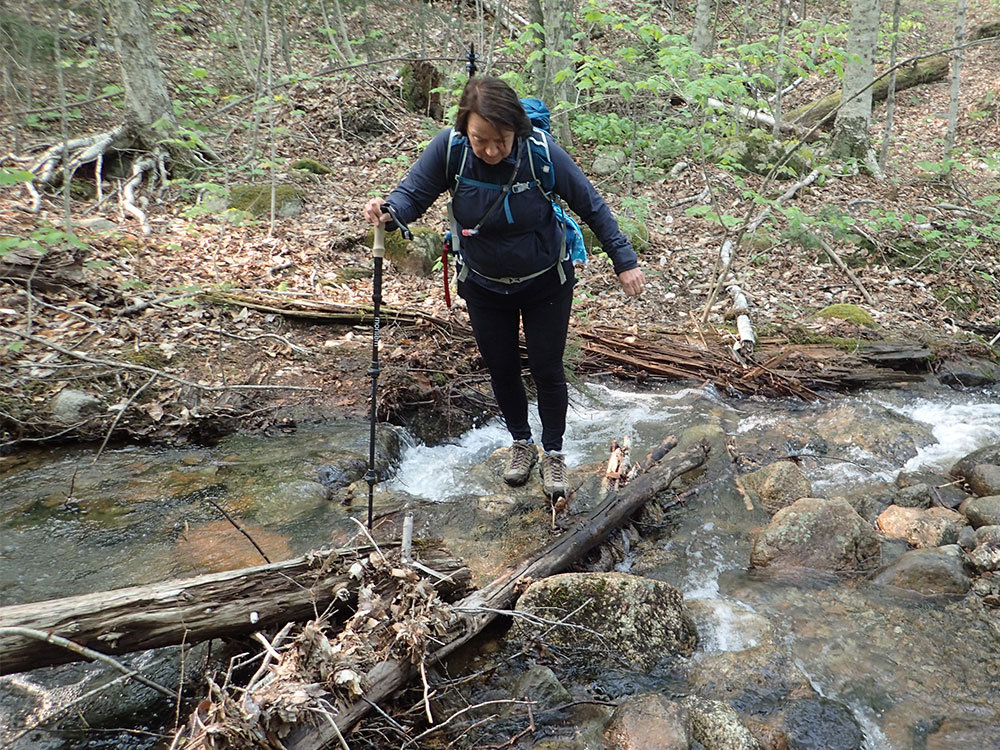 hiker crossing a stream in spring