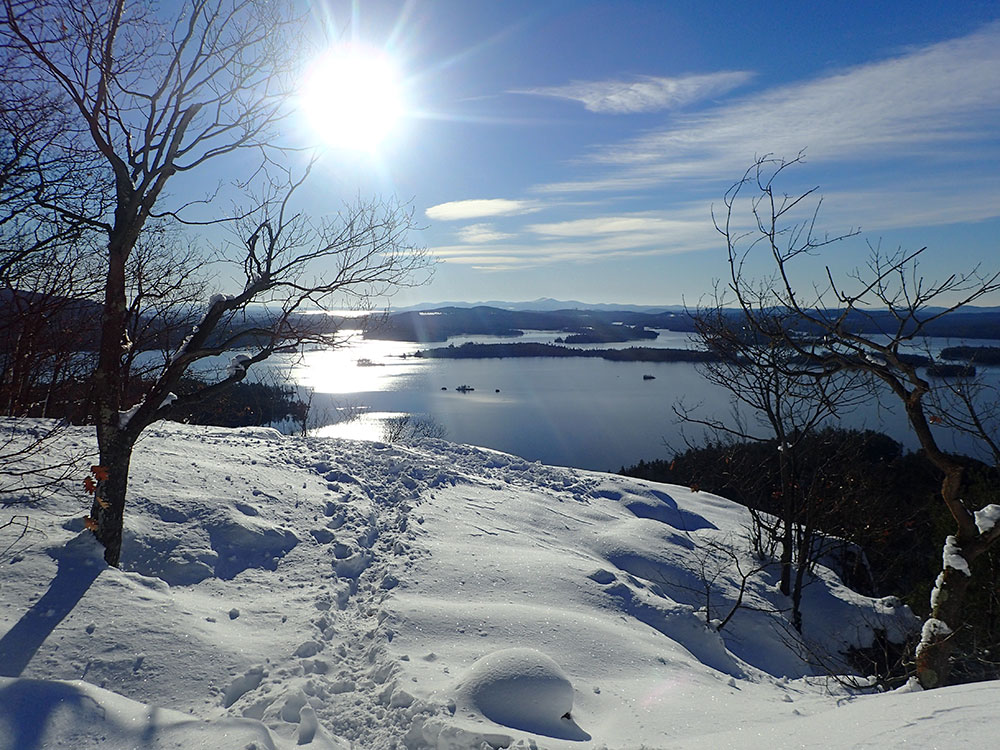 view of Squam Lake from the ledges looking into the sun