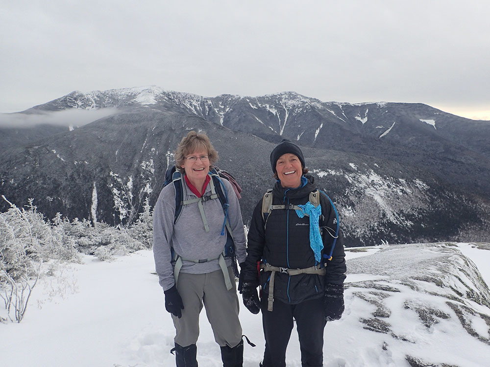 hikers on the summit of Cannon with snowy ridge behind them